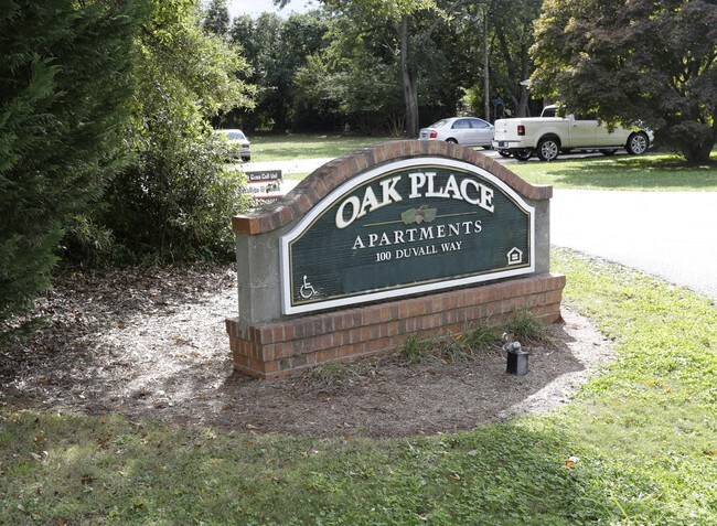 a sign for oak place apartments on the side of a road